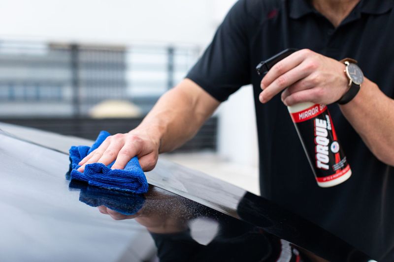 Automotive detailer using a polishing machine on a vehicle hood
